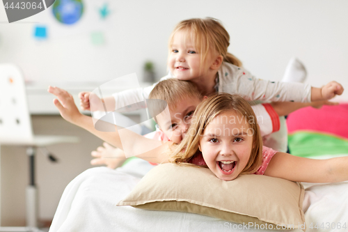 Image of happy little kids having fun in bed at home