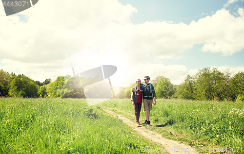 Image of happy couple with backpacks hiking outdoors