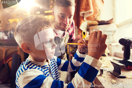 Image of father and son with ruler measure wood at workshop