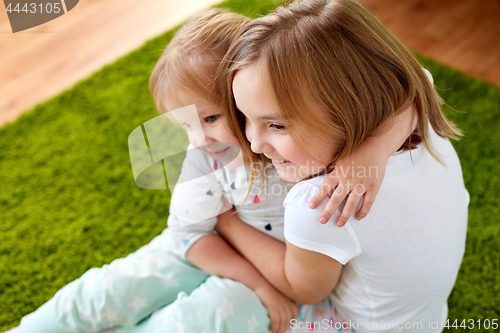 Image of happy little girls or sisters hugging at home