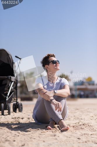 Image of Young mother with sunglasses relaxing on beach