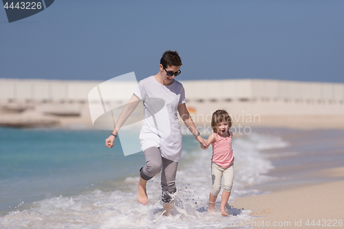 Image of mother and daughter running on the beach