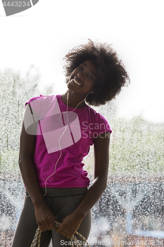 Image of portrait of young afro american woman in gym while listening mus