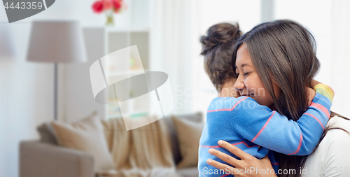 Image of happy mother and daughter hugging at home