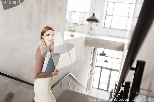 Image of happy woman with folder walking downstairs