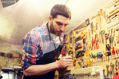 Image of carpenter working with plane and wood at workshop