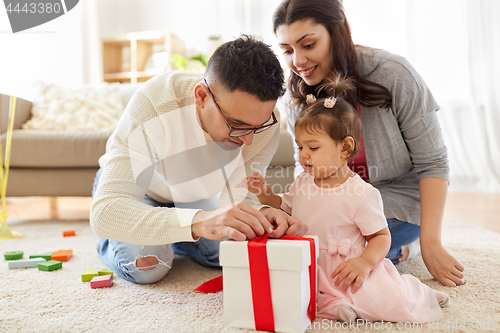 Image of baby girl with birthday gift and parents at home
