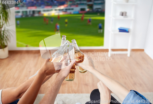 Image of friends clinking beer and watching soccer game