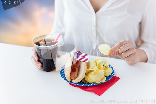 Image of close up of woman eating hot dog with cola