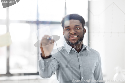 Image of businessman writing on glass board at office