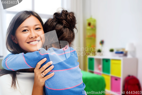 Image of happy mother and daughter hugging at home