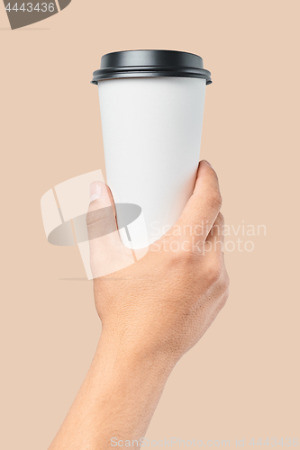 Image of Mockup of men\'s hand holding white paper large size cup with black cover