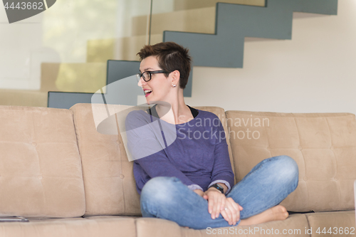 Image of portrait of a young beautiful woman sitting on the sofa