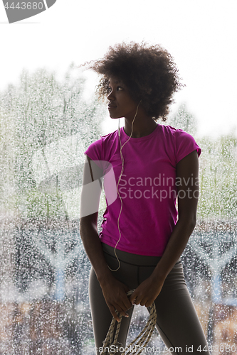 Image of portrait of young afro american woman in gym while listening mus