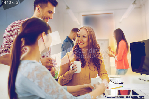 Image of happy creative team drinking coffee at office