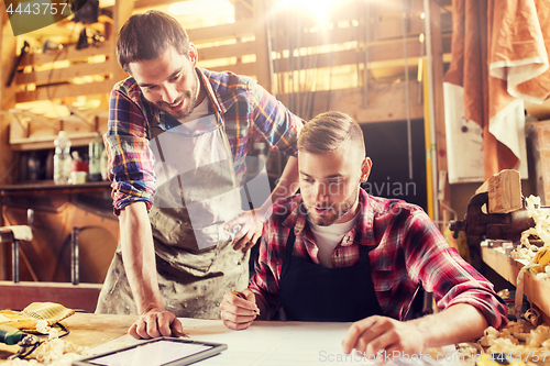 Image of workmen with tablet pc and blueprint at workshop