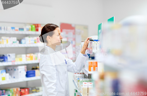 Image of happy female apothecary with drug at pharmacy