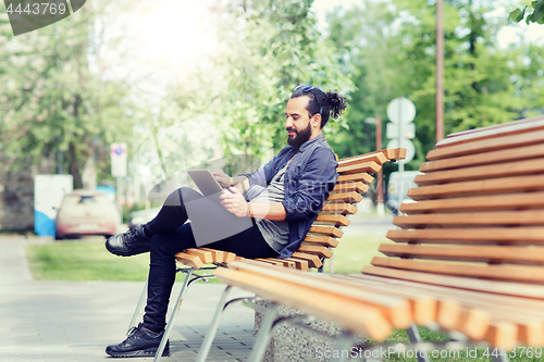 Image of man with tablet pc sitting on city street bench