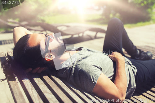 Image of happy man lying on street bench or sun bed 