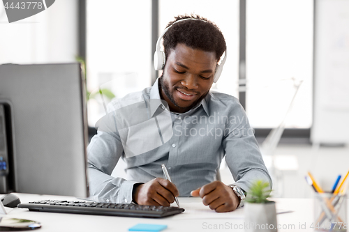 Image of businessman with headphones and papers at office