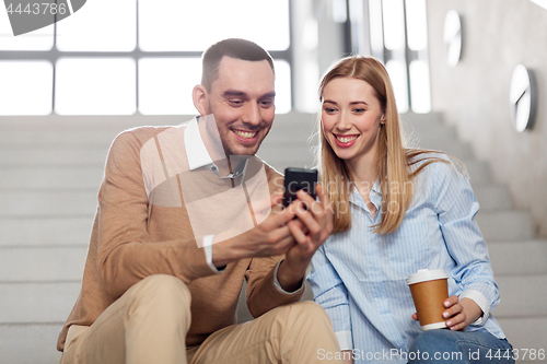 Image of man and woman with smartphone at office stairs