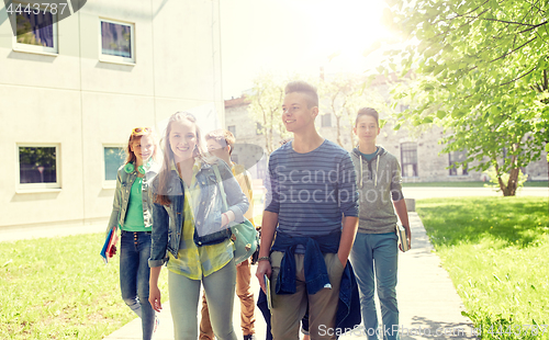 Image of group of happy teenage students walking outdoors