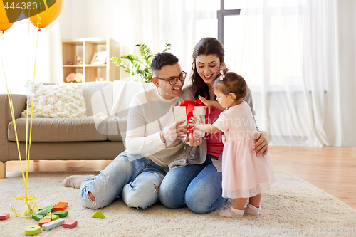 Image of baby girl with birthday gift and parents at home