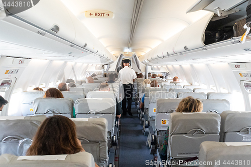 Image of Interior of commercial airplane with passengers on their seats during flight.