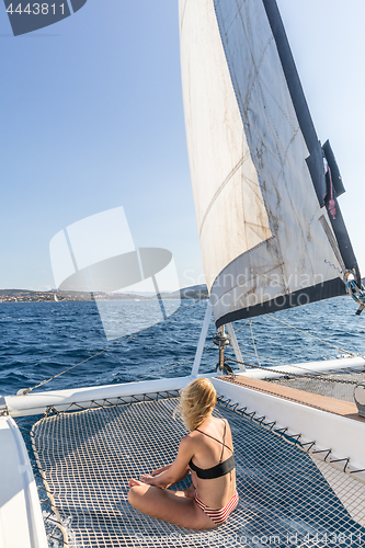 Image of Woman relaxing on a summer sailing cruise, sitting on a luxury catamaran near picture perfect Palau town, Sardinia, Italy.