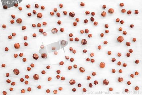 Image of Peeled and shelled hazelnuts on white wooden background