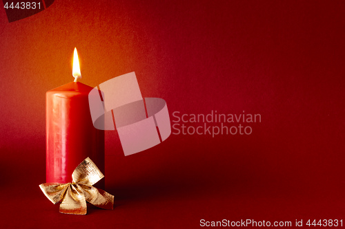 Image of Christmas decoration with a burning candle on red background