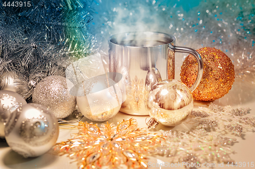 Image of Metal mug with hot steaming coffee, Christmas balls, Christmas tree.