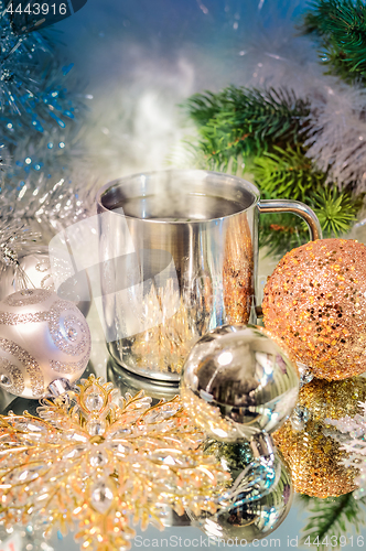 Image of Metal mug with hot steaming coffee, Christmas balls, Christmas tree.