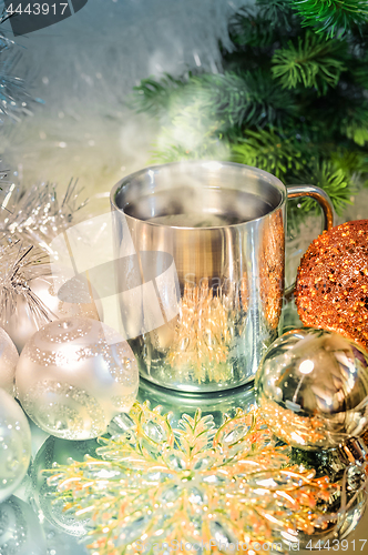 Image of Metal mug with hot steaming coffee, Christmas balls, Christmas tree.