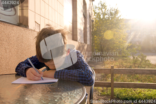 Image of Boy doing homework outdoors