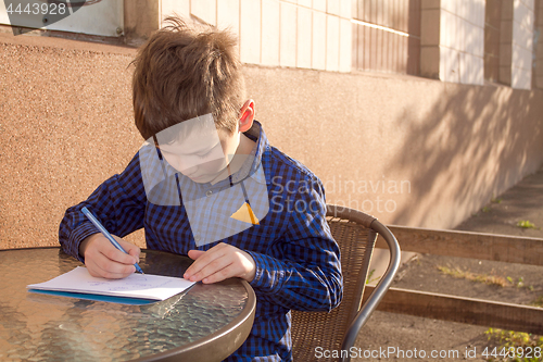 Image of Boy doing homework outdoors