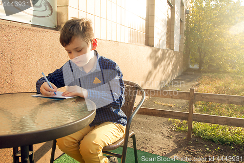 Image of Boy doing homework outdoors