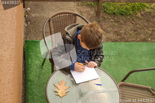 Image of Boy is doing homework outdoors