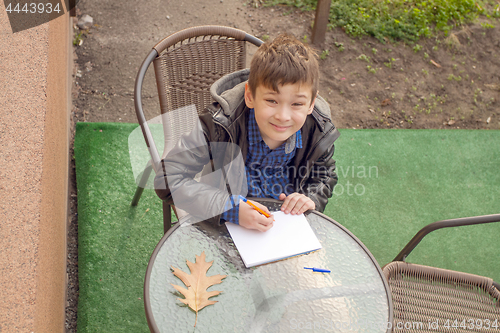 Image of Boy is doing homework outdoors