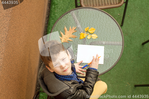 Image of Boy is doing homework outdoors