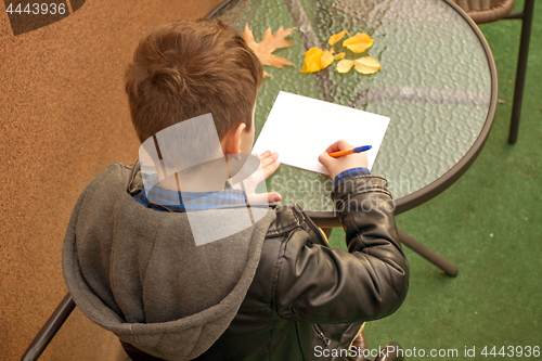 Image of Boy is doing homework outdoors