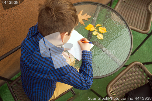 Image of Boy is doing homework outdoors