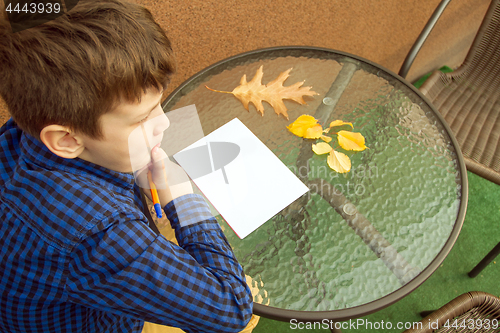 Image of Boy is doing homework outdoors