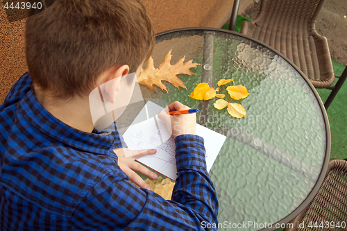 Image of Boy is doing homework outdoors