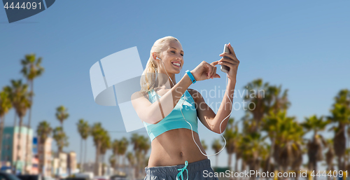 Image of woman with smartphone and earphones doing sports