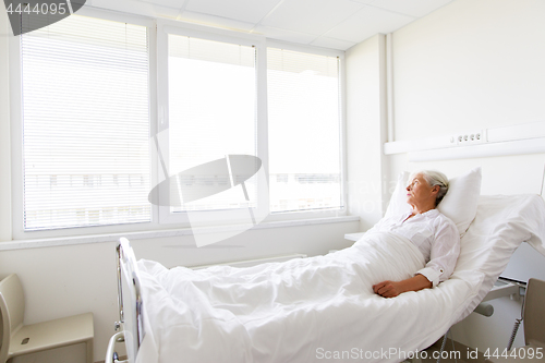 Image of sad senior woman lying on bed at hospital ward