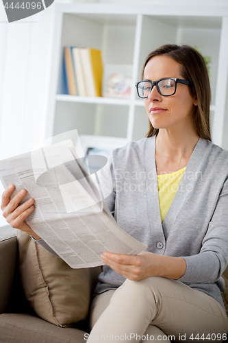 Image of woman in glasses reading newspaper at home
