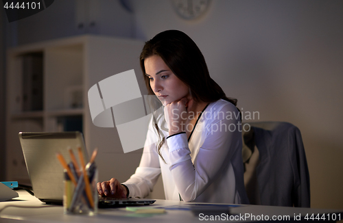 Image of businesswoman with laptop at night office