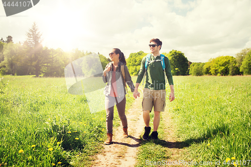 Image of happy couple with backpacks hiking outdoors