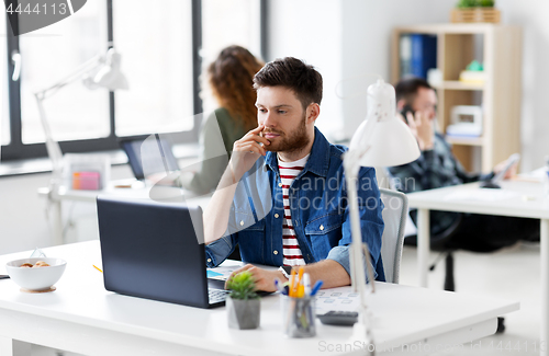 Image of creative man with laptop working at office